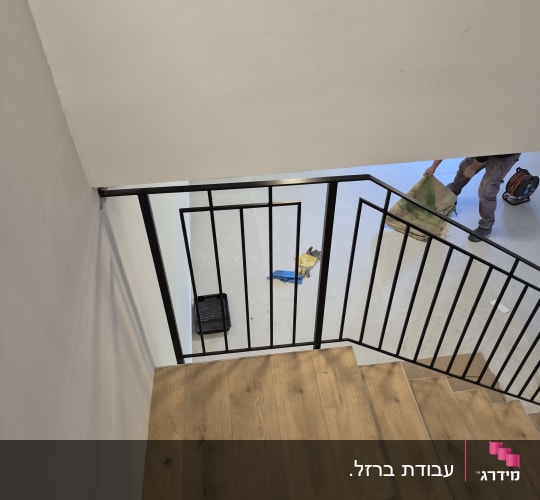 מעקה מתכת במדרגות עץ עם כלים על הרצפה